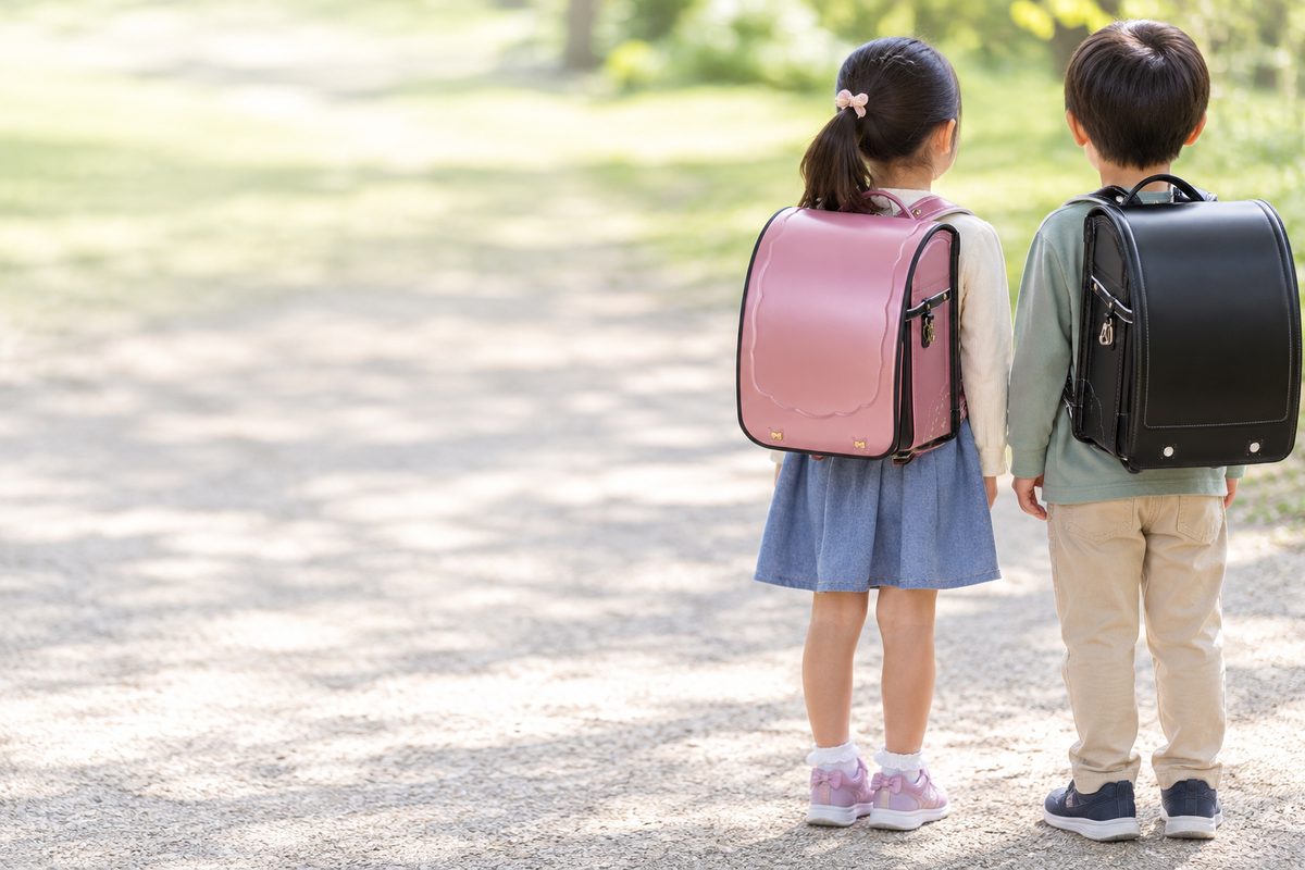 フィットちゃんのミオコフレ キャンディピンク×クロを背負った女の子と、フィットちゃんのタフボーイ ブラックを背負った男の子の後ろ姿