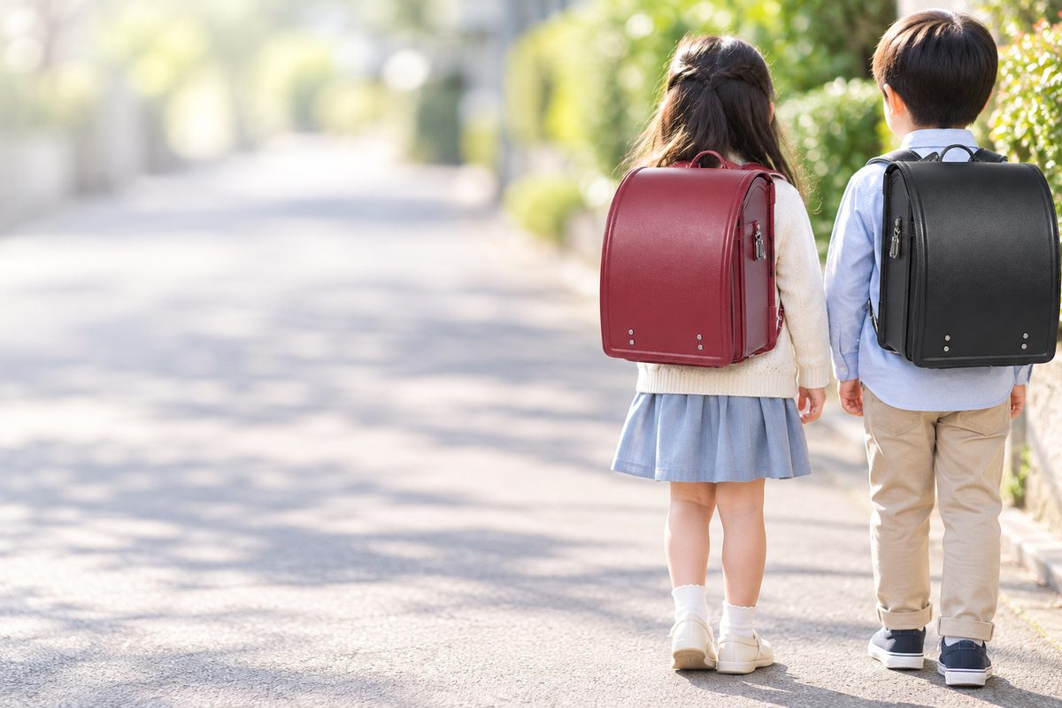 土屋鞄のRECO 牛革ハイブリッド ディープレッドを背負った女の子と、土屋鞄のRECO 牛革ハイブリッド ブラックを背負った男の子の後ろ姿